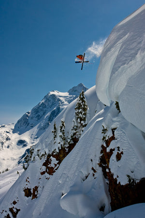 Open image in slideshow, Jamie Pierre droping a large cornice in the Mt. Baker Ski ARea Backcountry with Mount Shuskan in the Background
